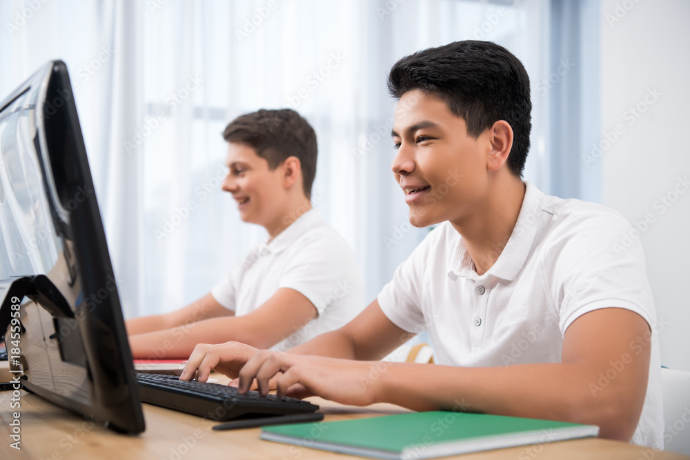 young happy teenager boys studying on computers young happy teenager boys studying on computers