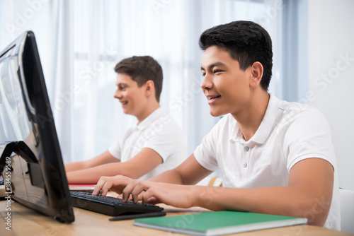 young happy teenager boys studying on computers