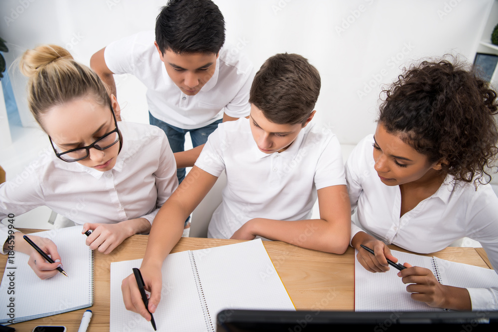 young students writing something in notebooks young students writing something in notebooks