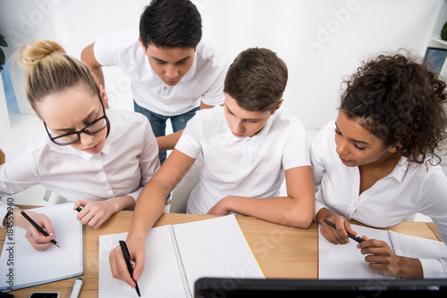 young students writing something in notebooks