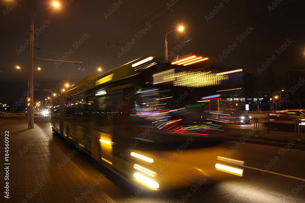 The motion of a blurred bus on the avenue in the evening