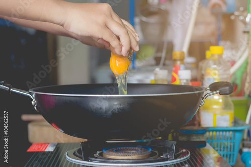 Hand frying egg in a frying pan in kitchen.Concept cooking and easy food.