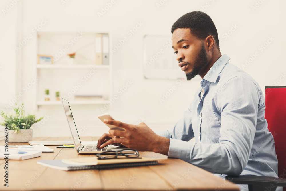 Fototapeta premium Young black businessman using mobile phone