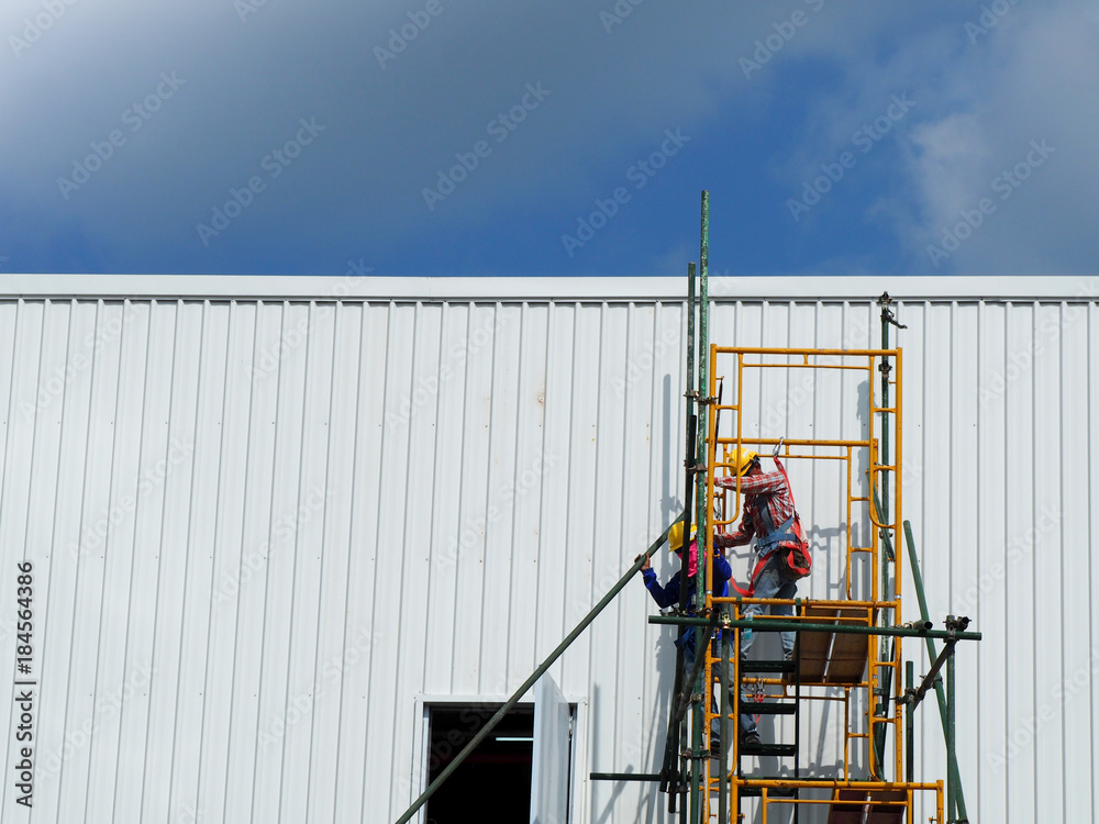 Construction workers working on scaffolding, Man Working on the Working at height with blue sky at construction site