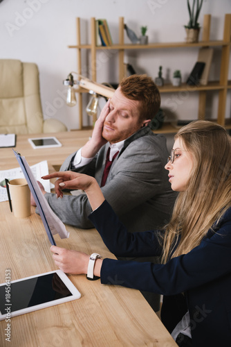 exhausted businesspartners lookign at documents together at office photo