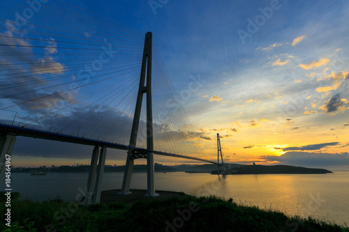 Fototapeta Naklejka Na Ścianę i Meble -  Amazing zooming out aerial view of the Russky Bridge, the world's longest cable-stayed bridge, and the Russky (Russian) Island in Peter the Great Gulf in the Sea of Japan. Sunrise. Vladivostok, Russia