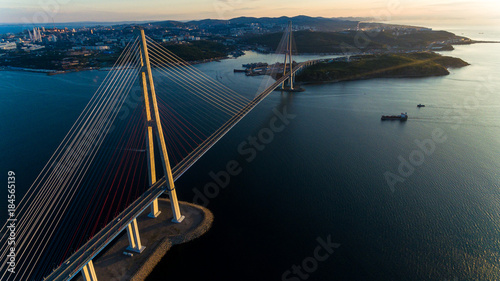 Amazing zooming out aerial view of the Russky Bridge, the world's longest cable-stayed bridge, and the Russky (Russian) Island in Peter the Great Gulf in the Sea of Japan. Sunrise. Vladivostok, Russia photo