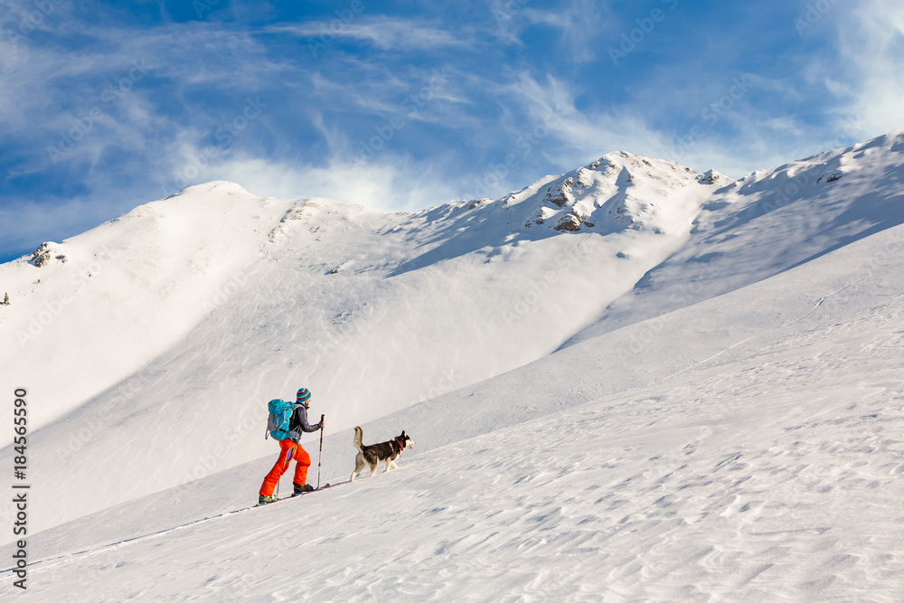 Young man backcountry skiing, going uphill on the mountain, with