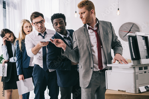 group of businesspeople standing in queue for copier at office