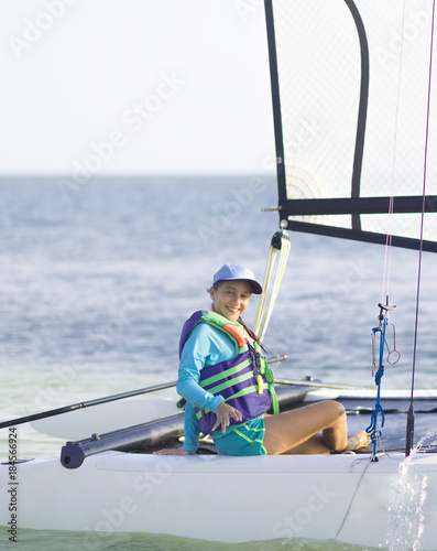 Beautiful teenager sailing catamaran in beautiful sunset. © Herjua