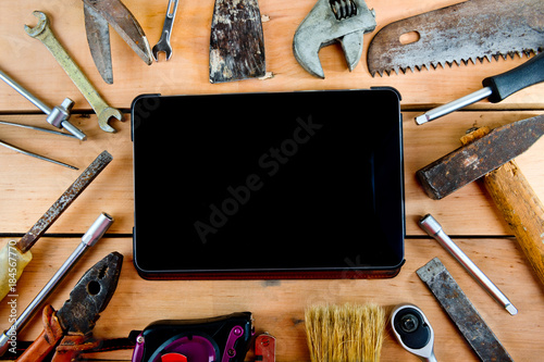 Tablet and old tools on a natural wooden background.