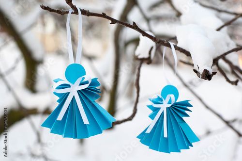Paper angels on branch with snow.