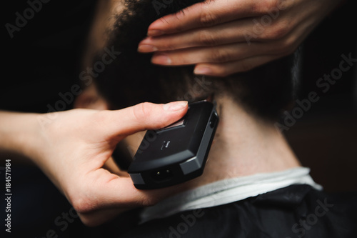 Master cuts hair and beard of men in the barbershop, hairdresser makes hairstyle for a young man