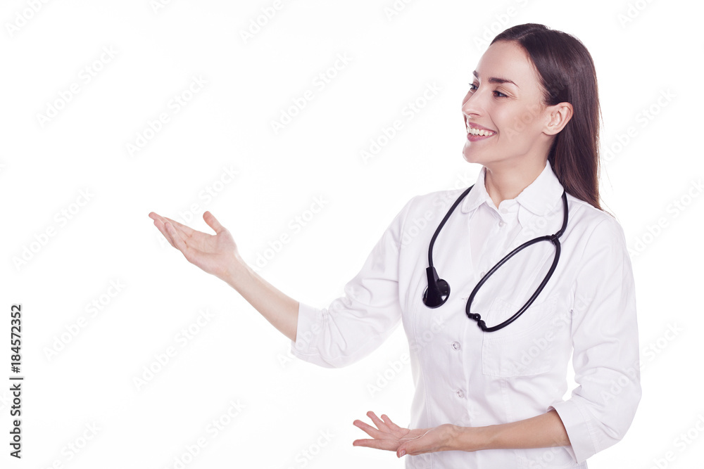 Smiling attractive modern doctor with stethoscope isolated on white background and pointing on copyspace Smiling attractive modern doctor with stethoscope isolated on white background and pointing on copyspace