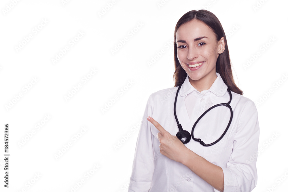 Smiling attractive modern doctor with stethoscope isolated on white background and pointing on copyspace Smiling attractive modern doctor with stethoscope isolated on white background and pointing on copyspace