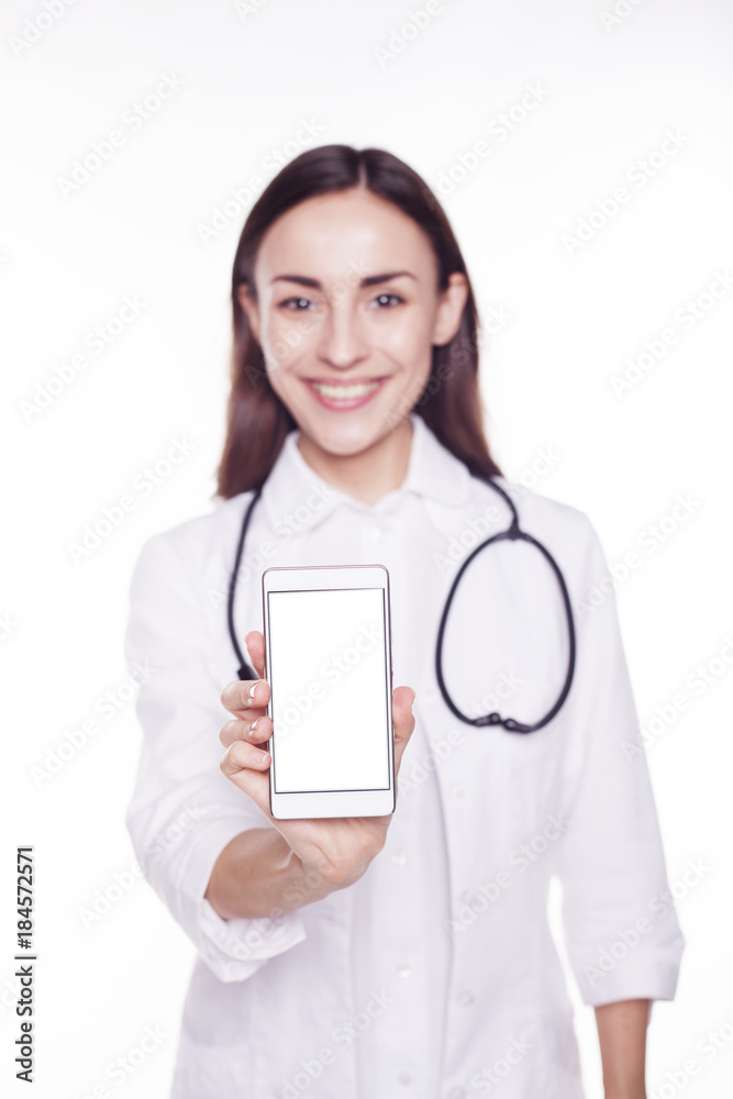 Beautiful smiling woman doctor with a stethoscope holds in her hand a phone with a white screen and shows it to the camera. Beautiful smiling woman doctor with a stethoscope holds in her hand a phone with a white screen and shows it to the camera.