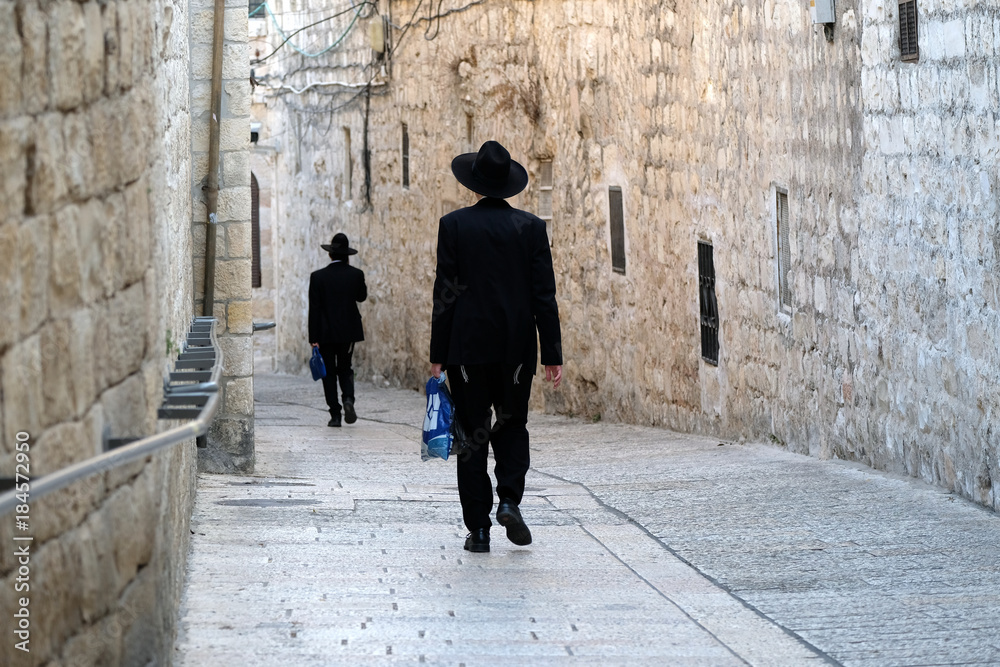 Fototapeta premium Dwóch nierozpoznanych religijnych Żydów idących ulicą Starego Miasta w Jerozolimie.