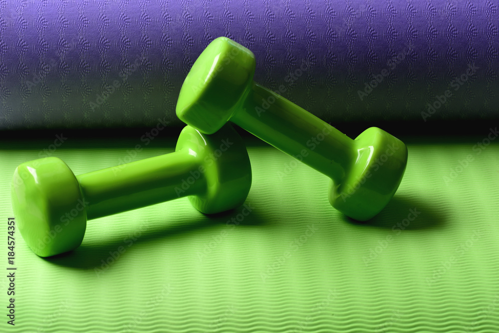Fototapeta premium Barbells lying on yoga mat, close up. Sports and health