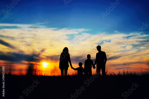  Father  mother  and children hold hands on a sunset background.