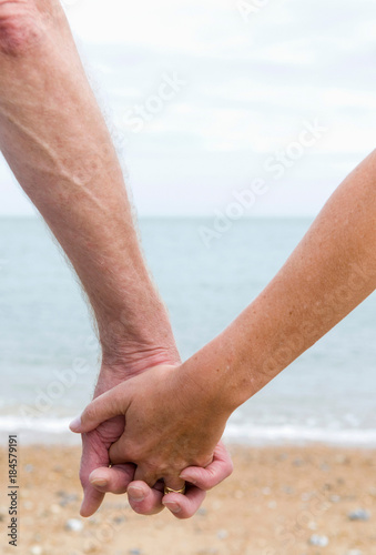 Seniors hold hands on beach