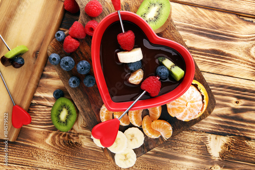 chocolate fondue with fruits assortment on wooden cutting board