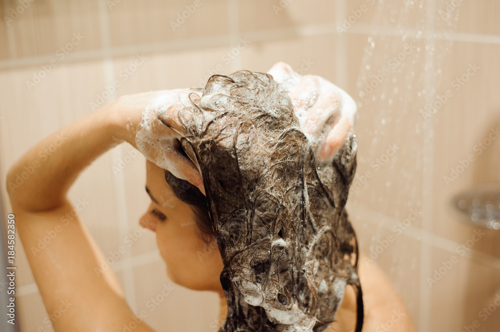 Beautiful woman taking a shower. Washing hair with Shampoo.