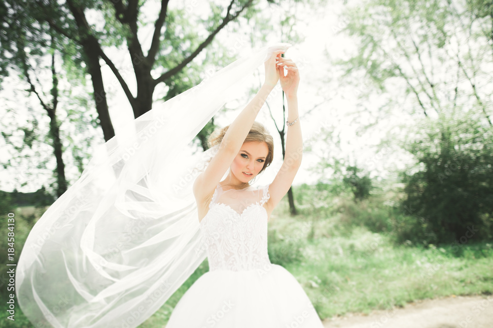 Beautiful bride in elegant white dress holding bouquet posing in park Beautiful bride in elegant white dress holding bouquet posing in park