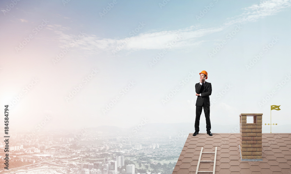 Engineer man standing on roof and looking away. Mixed media Engineer man standing on roof and looking away. Mixed media
