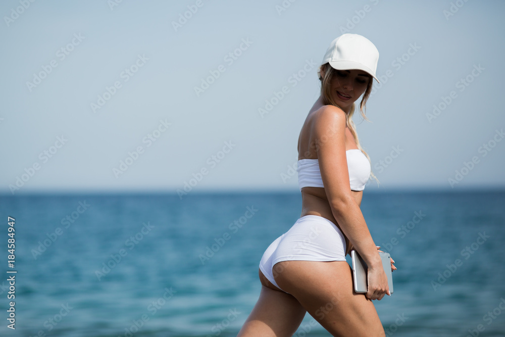 Young beautiful woman in sport suit is using her tablet on the beach Young beautiful woman in sport suit is using her tablet on the beach