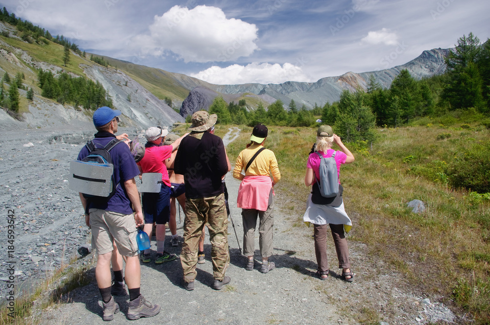 Group of people hikers with backpacks standing and looking at the mountains at sunny day Altai Mountains Siberia, Russia