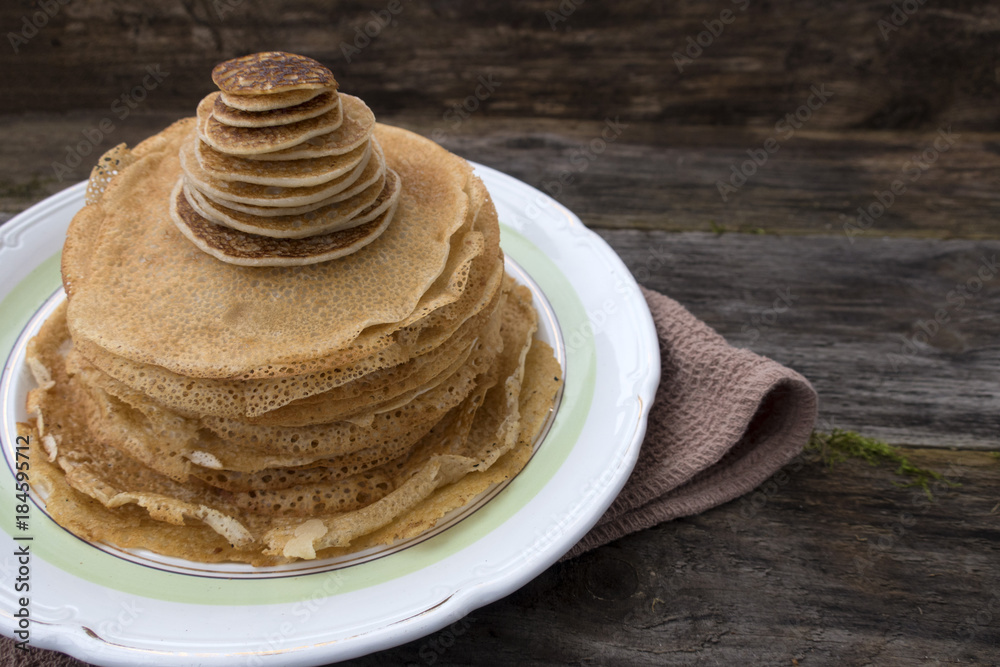 Large and small pancakes located on an old wooden table. Close-up and place for copy space. Large and small pancakes located on an old wooden table. Close-up and place for copy space.
