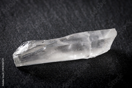 Uncut diamond, white quartz and raw gemstone concept with a white clear mineral stone against a dark background