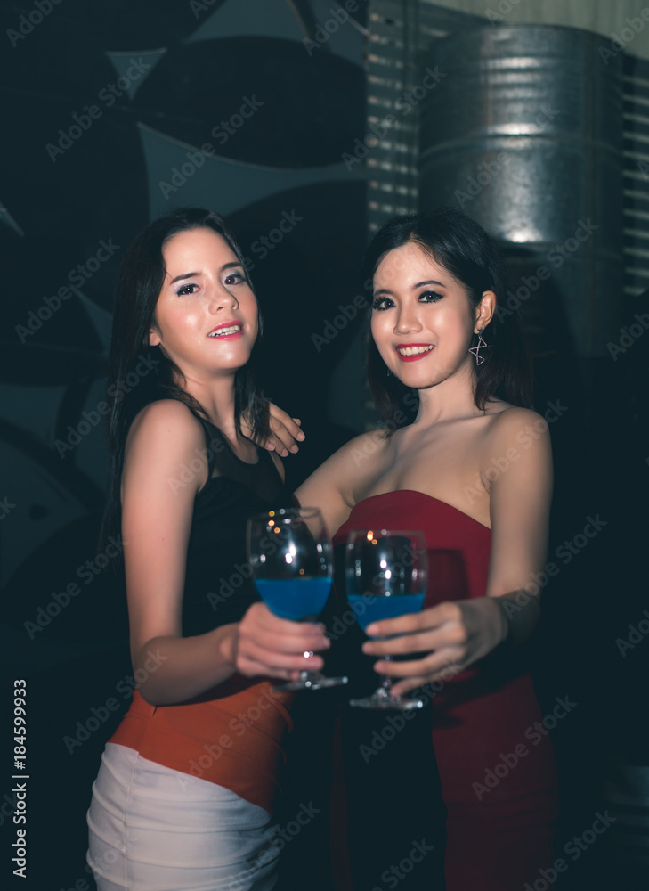 Friends Enjoying Cheerful Party and Clinking Glass of Cocktail in Night Club