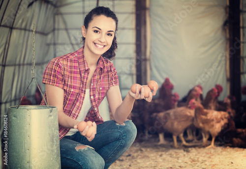 Portrait of young woman farmer holding fresh eggs in hands in henhouse