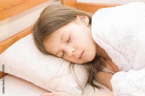 Маленькая девочка спит в своей кровати под одеялом