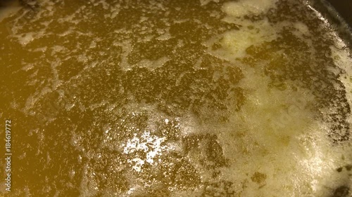 Ghee is clarified butter. Boiling yellow butter with small white bubbles.