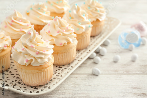 Tray with tasty cupcakes for baby shower party on table photo