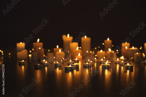 Burning candles on floor in darkness photo