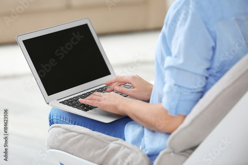 Young woman using laptop at home, closeup