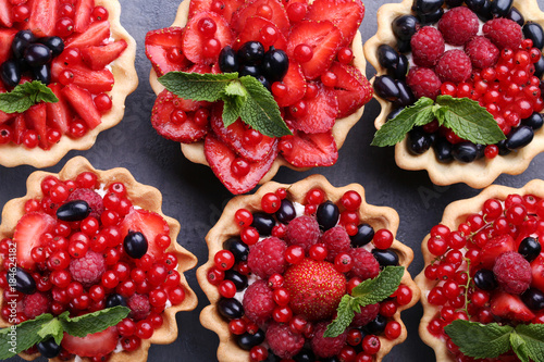 Dessert tartlets with berries on grey wooden table