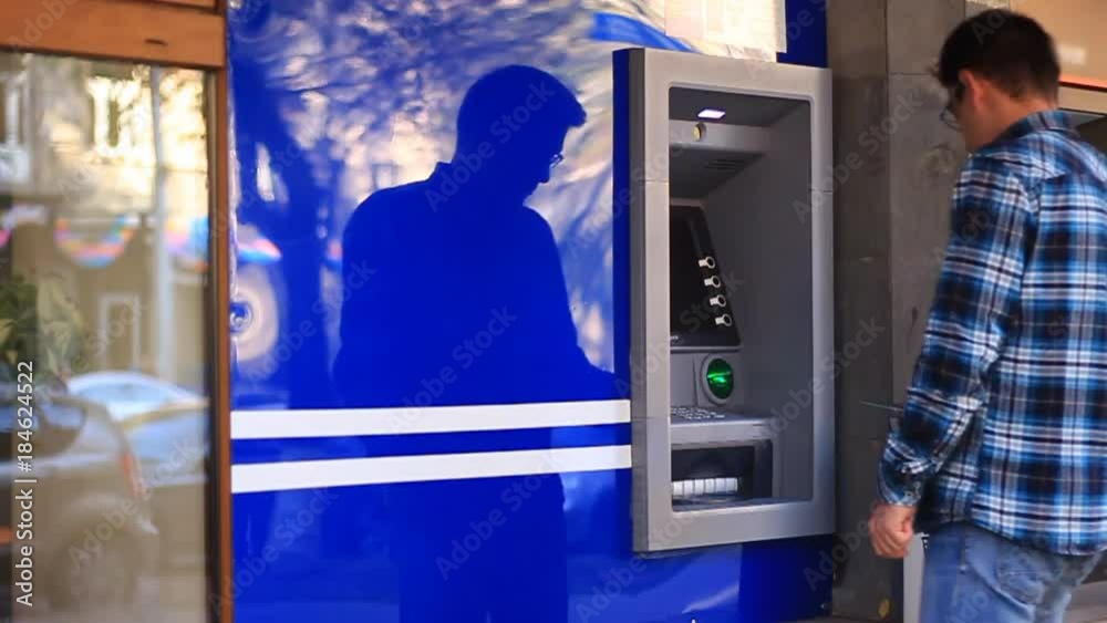 A young guy approaches an ATM, withdrawal money, and departs from an ATM A young guy approaches an ATM, withdrawal money, and departs from an ATM