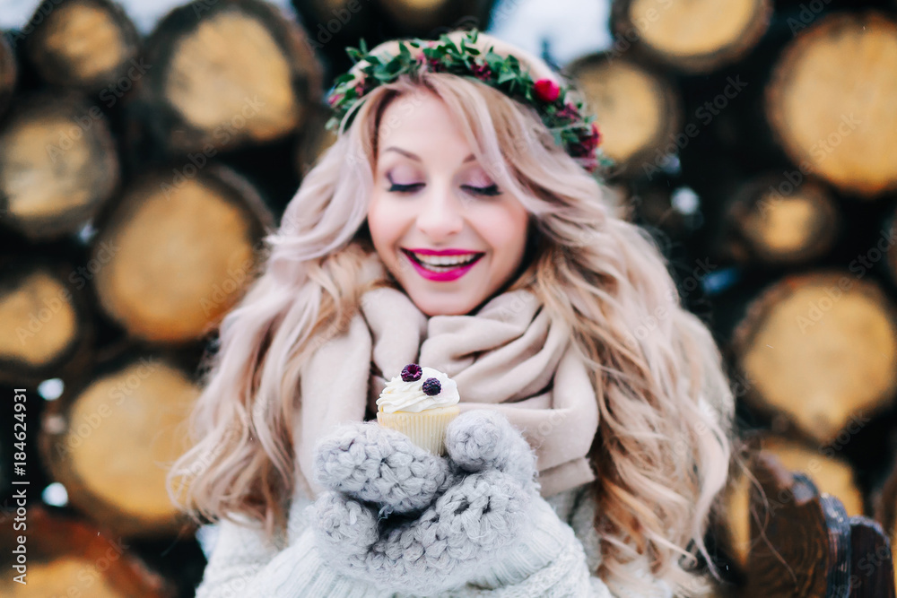 Cheerful blonde girl with curly hair hold a cupcake. Selective focus on the cupcake. Artwork Cheerful blonde girl with curly hair hold a cupcake. Selective focus on the cupcake. Artwork