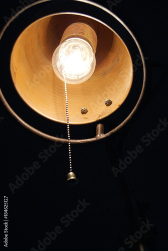 Closeup of a lamp with lightbulb surrounded by darkness during the night