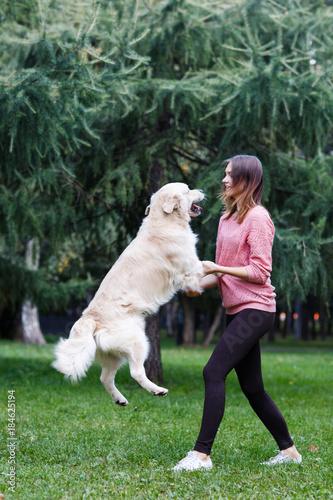 Fotografía Image of brunette and jumping dog on green lawn
