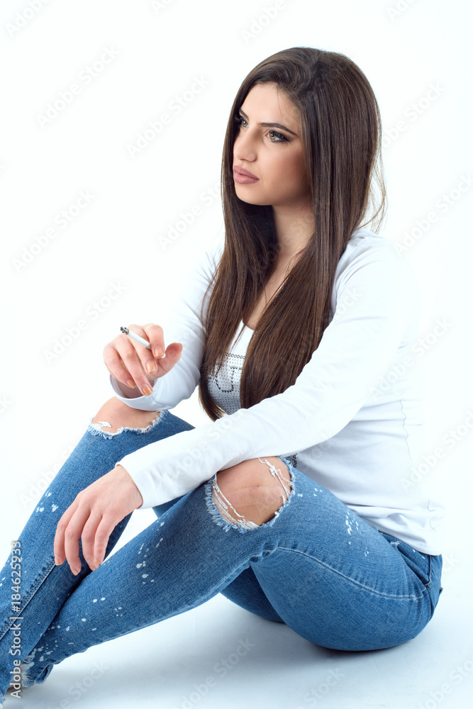 Beautiful young girl wearing a jeans and white t-shirt and smoking cigaret  Stock Photo | Adobe Stock
