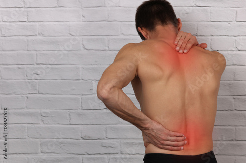 Muscular Man suffering from back and neck pain. Incorrect sitting posture problems, Muscle spasm, rheumatism. Pain relief , chiropractic concept. Sport exercising injury