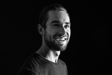 Young handsome man smiling on black background