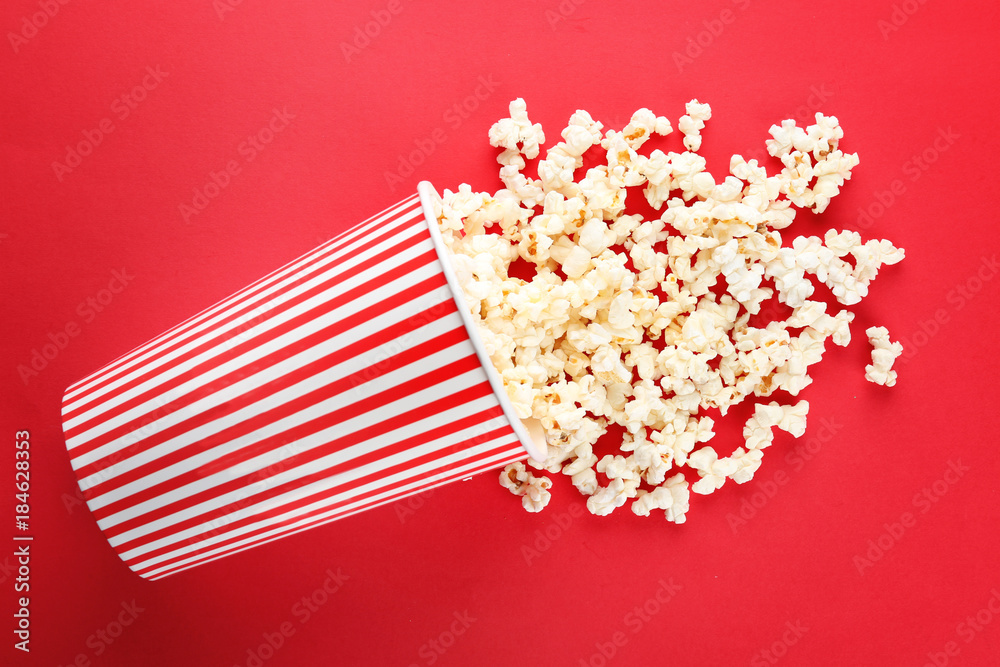 Cup with popcorn on color background
