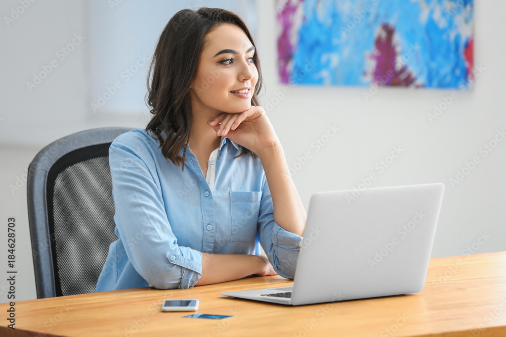 Thoughtful young woman with laptop in office Thoughtful young woman with laptop in office