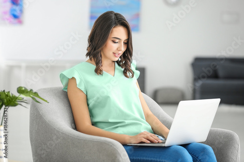 Young woman using laptop at...